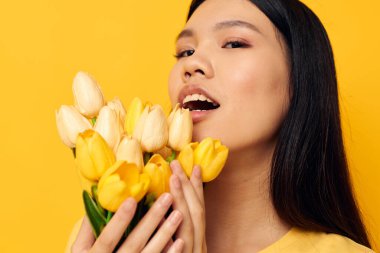 Sarı tişörtlü, çiçekli bir buket tatili olan çekici Asyalı genç kadın. Değişmemiş yaşam tarzı.