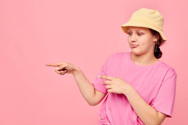 Bej rengi Panama tişörtlü çekici genç bir kadın stüdyo modelinin el hareketlerini yapıyor.