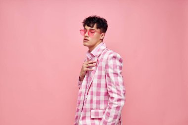 Genç bir adamın portresi pembe gözlüklü kareli ceket modası pembe arka plan değiştirilmemiş.
