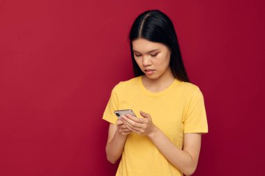 Kadın telefonu kırmızı arka planda kullanıyor.