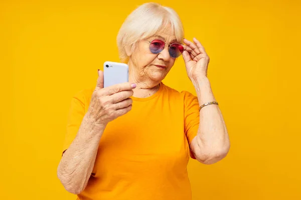 Anciana sonriente hablando por teléfono en tecnologías de gafas amarillas — Foto de Stock