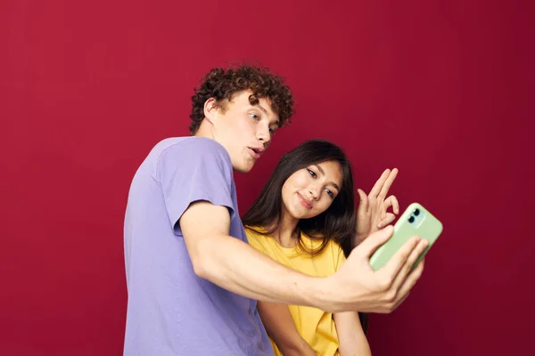 Adolescenti in T-shirt colorate con borse Shopping sfondo rosso inalterato — Foto Stock