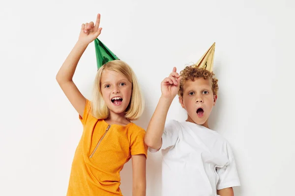 Imagen de chico y chica positivos en gorras multicolores cumpleaños fiesta emoción fondo claro — Foto de Stock