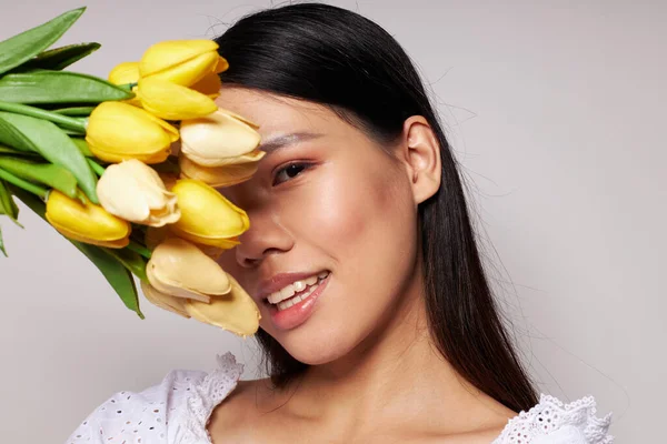 아시아의 아름다운 젊은 여자가 꽃을 피우는 모습은 변함 이 없는 밝은 배경을 배경으로 한다 — 스톡 사진