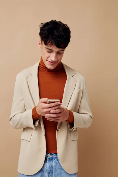 Портрет молодого чоловіка в бежевій куртці, що говорить по телефону світлий фон незмінний — стокове фото