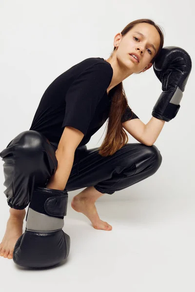 Femme sportive en gants de boxe sur le sol en t-shirt noir fond clair — Photo