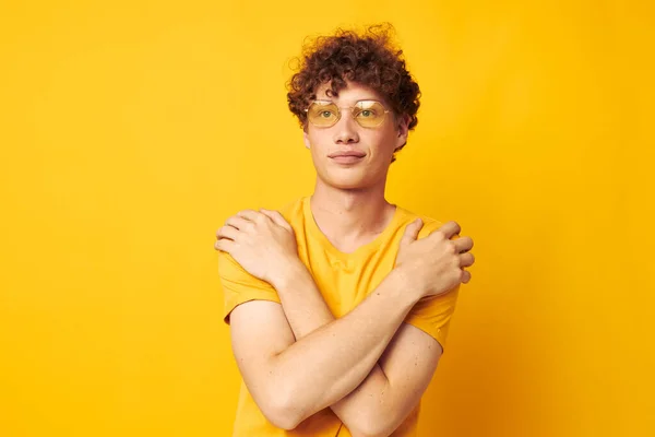 Portré egy fiatal göndör férfi sárga póló szemüveg divat kéz gesztusok elszigetelt háttér változatlan — Stock Fotó