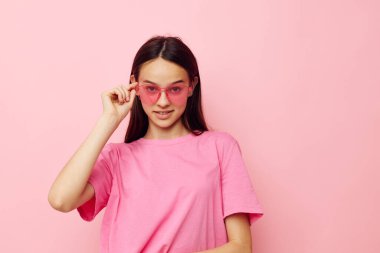Pembe tişörtlü güzel bir kadın. Günlük kıyafetler. Pembe arka plan.