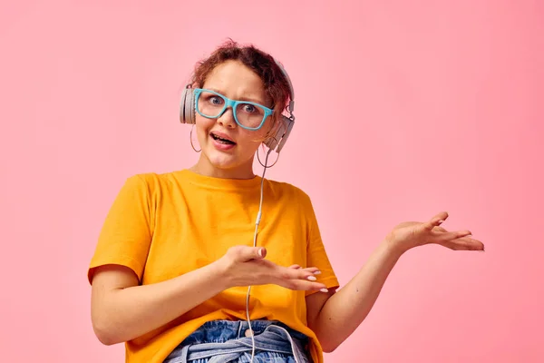 Hübsche Frau mit blauer Brille hört Musik über Kopfhörer isolierte Hintergründe unverändert — Stockfoto