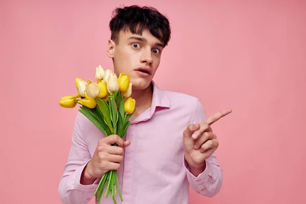 Foto de novio joven romántico en una camisa rosa con un ramo de flores haciendo gestos con las manos Estilo de vida inalterado — Foto de Stock