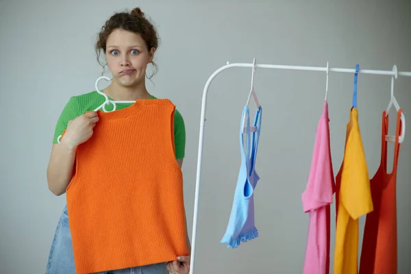 Portrait of a young woman ironing clothes on a hanger wardrobe cropped view unaltered — Stock fotografie