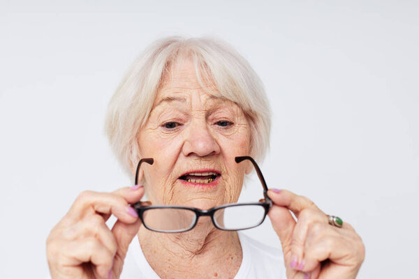 emotional elderly woman in casual t-shirt and glasses light background