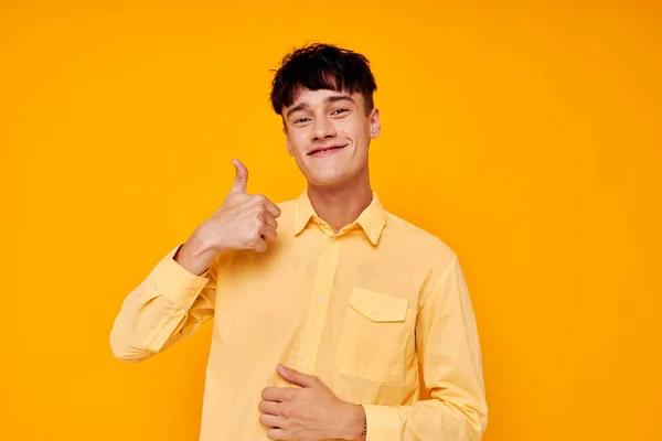 Cheerful young man in a yellow shirt gestures with his hands emotions — Stockfoto