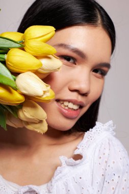 Bir buket çiçekle büyüleyici genç Asyalı kadın. Arka planda hiç değişmeden gülümse.