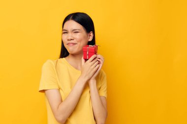 Sarı tişörtlü, genç Asyalı çekici bir kadın. Tatil hediyesi. Duyguları değişmemiş, stüdyo modeli.