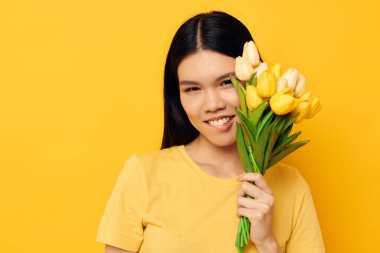 Sarı tişörtlü bir kadın ve bir buket çiçekli bir tişört. Tatil tarzı değiştirilmemiş.