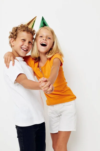 Imagen de chico y chica positivos en gorras multicolores cumpleaños fiesta emoción fondo claro — Foto de Stock
