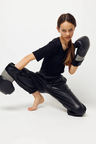 Jovem mulher em luvas de boxe no chão em preto t-shirt isolado fundo — Fotografia de Stock