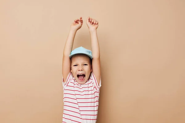 Portret van vrolijk lachend kind meisje in blauwe caps gestreepte t-shirt emoties beige achtergrond — Stockfoto