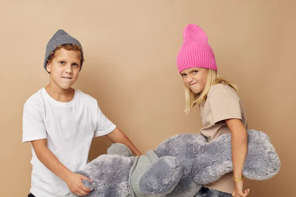 Photo of two children in multi-colored hats entertainment posing beige background — Stockfoto