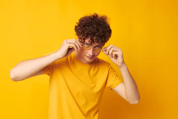 Fiatal göndör hajú férfi sárga póló szemüveg divat kéz gesztusok monokróm lövés — Stock Fotó