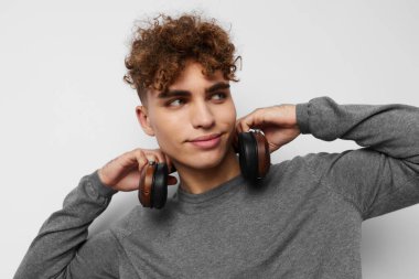 Gri süveter kulaklıklı yakışıklı genç adam. Moda arkaplanı.