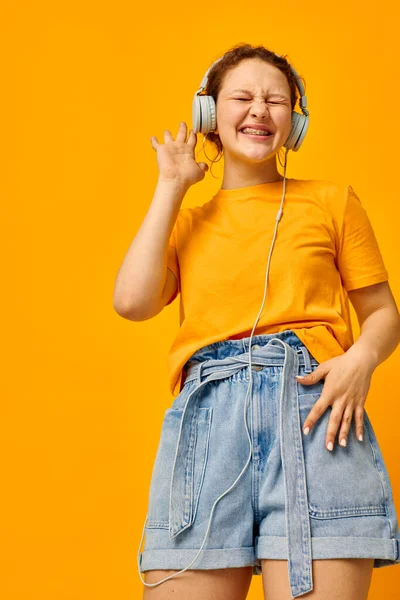 Grappig meisje luisteren naar muziek op hoofdtelefoon jeugd stijl geel achtergrond ongewijzigd — Stockfoto