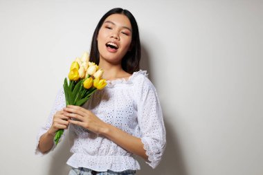 Beyaz gömlekli, Asyalı bir kadın. Çiçekler. Stüdyo modeli gibi poz veriyor.