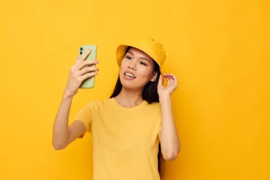 Çekici genç Asyalı kadın telefonda konuşuyor. Moda pozu veriyor. Geçmişi değişmemiş.