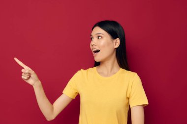 Sarı tişörtlü güzel bir esmer. El kol hareketi yapıyor. Eğlenceli, izole bir arka plan.