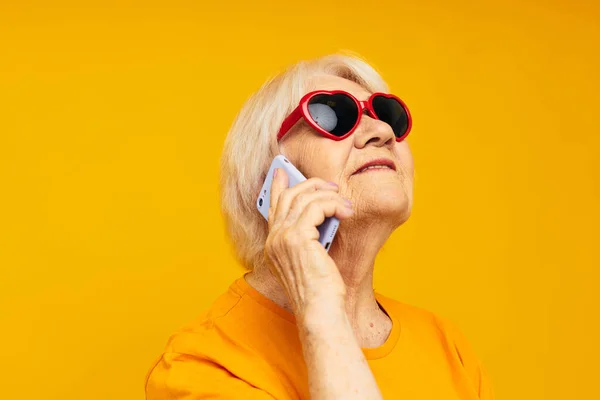 Siyah gözlüklü yaşlı bir kadının portresi izole edilmiş arka planda telefonla konuşuyor. — Stok fotoğraf