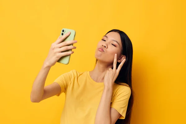 Ritratto Asiatica bella giovane donna in una t-shirt gialla guardando il telefono posa Stile di vita inalterato — Foto Stock