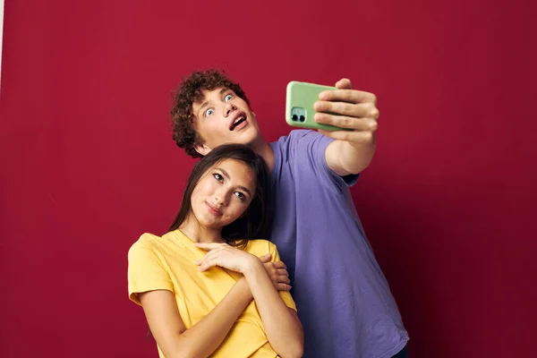 Giovane uomo e ragazza stile moderno emozioni divertimento telefono rosso sfondo — Foto Stock