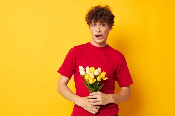 Молодий кучерявий чоловік у червоній футболці букет квітів святковий подарунок Стиль життя незмінний — стокове фото