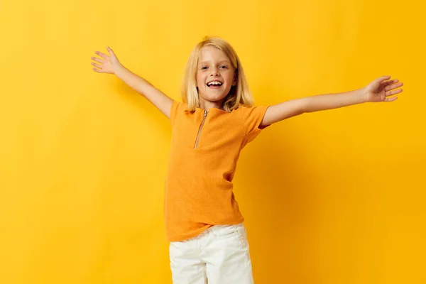Sarı tişörtlü güzel küçük kız gülümsemesi ile stüdyoda çocukluk hayatı pozu veriyor. — Stok fotoğraf
