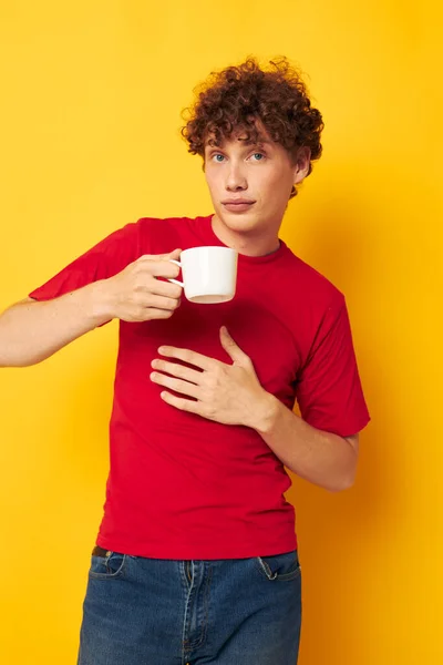 赤のTシャツを着た可愛い赤髪の男は、白い帽子を手に取り、背景を変えずに隔離しました — ストック写真