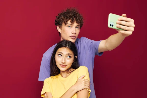 Una pareja joven en camisetas coloridas con un teléfono Estilo juvenil — Foto de Stock