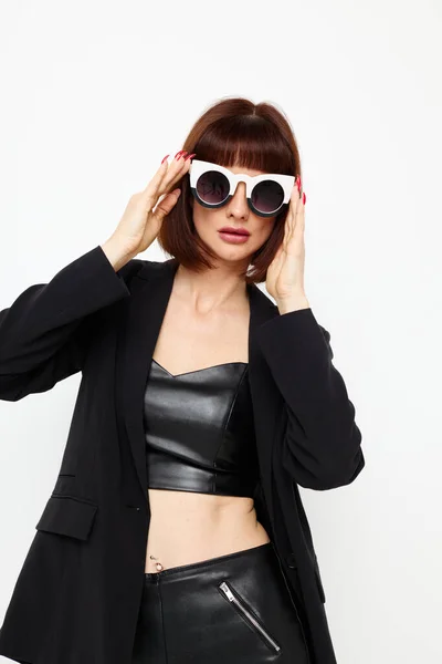 Foto bonita mujer posando con gafas de sol un traje de cuero chaqueta negra fondo aislado — Foto de Stock