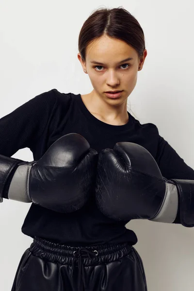 Siyah pantolonlu, boks eldivenli ve arka planda tişört giyen genç bir kadın. — Stok fotoğraf