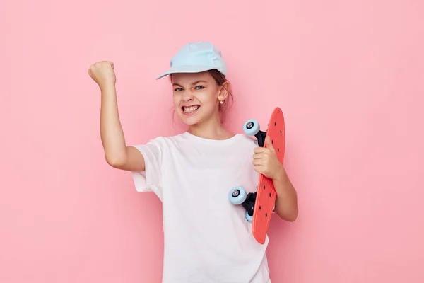 Портрет счастливой улыбающейся девочки кепка в белой футболке скейтборд изолированный фон — стоковое фото
