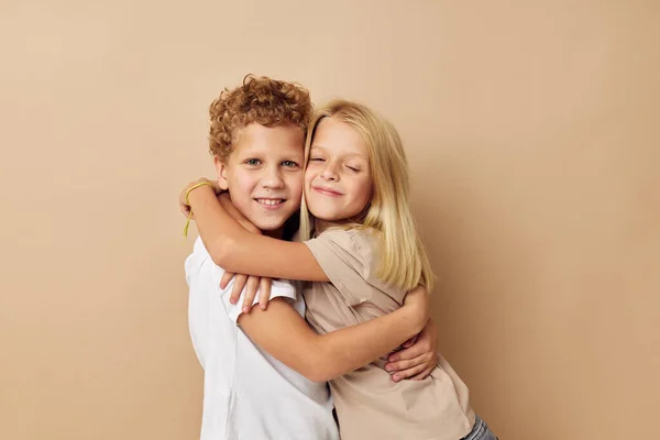 Chico y chica en camisetas abrazos beige fondo amistad — Foto de Stock