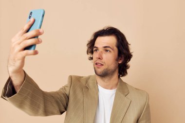 Takım elbiseli bir adam telefon bej arka planına bakarak duygularını belli ediyor.