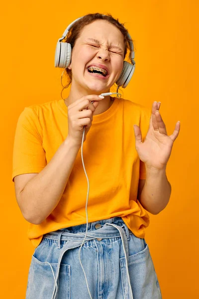 Divertente ragazza giallo t-shirt cuffie intrattenimento musica divertimento isolato sfondi inalterati — Foto Stock