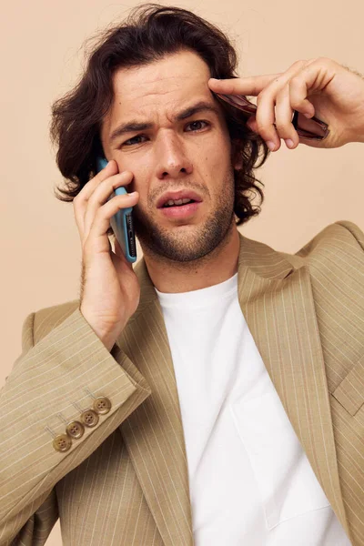 Hombre alegre en un traje posando emociones hablando en el fondo beige teléfono —  Fotos de Stock