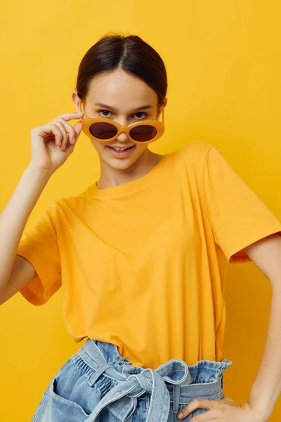 Attraktiv kvinna i solglasögon en gul t-shirt sommar stil isolerad bakgrund — Stockfoto