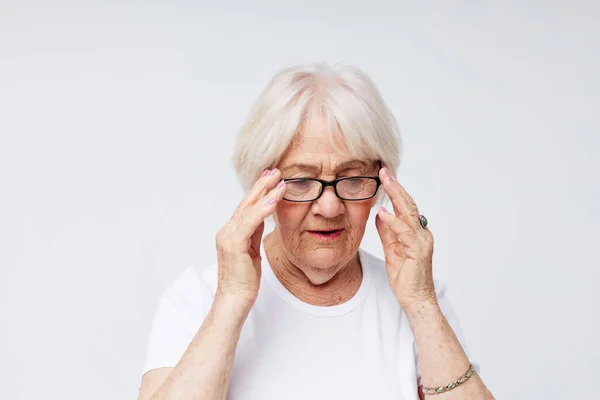 Photo of retired old lady in casual t-shirt and glasses light background