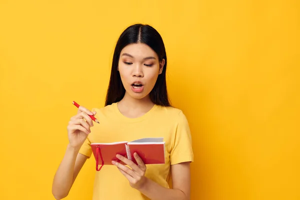 Charmante jeune femme asiatique dans un t-shirt jaune carnet rouge formation fond jaune inchangé — Photo
