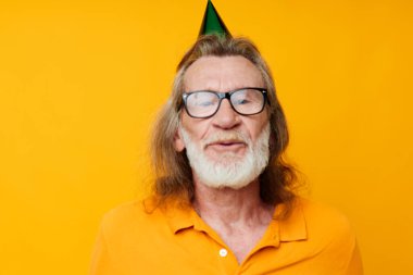 Sarı tişörtlü, şapkalı, komik sarı arka planlı yaşlı adam portresi.