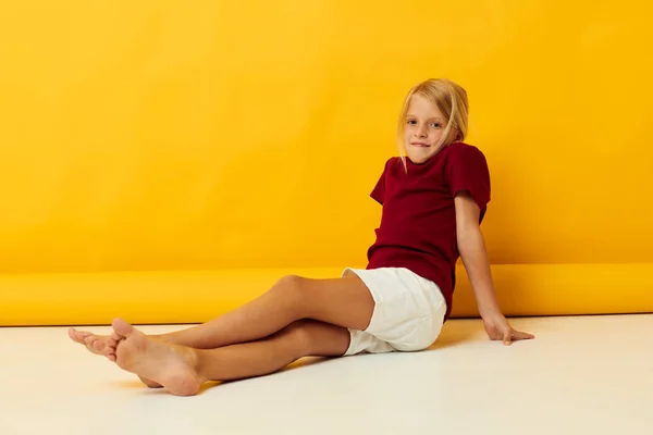 Küçük kız sarı arka planda yerde oturuyor. — Stok fotoğraf