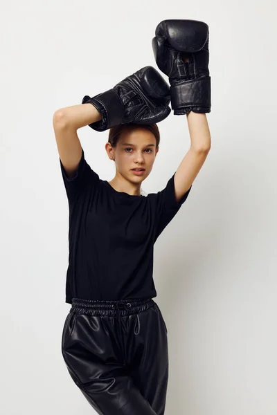 Hermosa chica en negro deportes uniforme guantes de boxeo posando fondo aislado — Foto de Stock